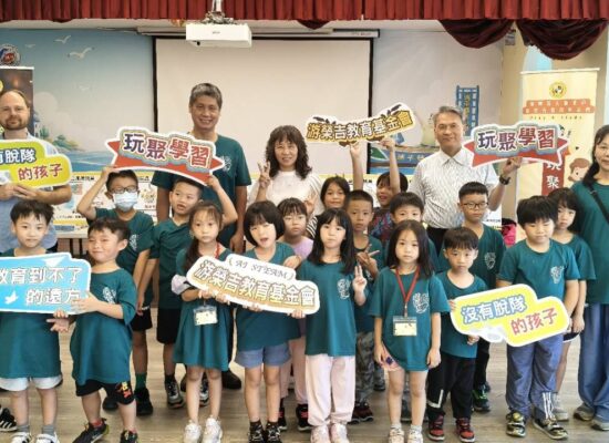 瑞平國小學生與師長在兒童傷害預防課程中合影,手持玩聚學習與教育公益標語