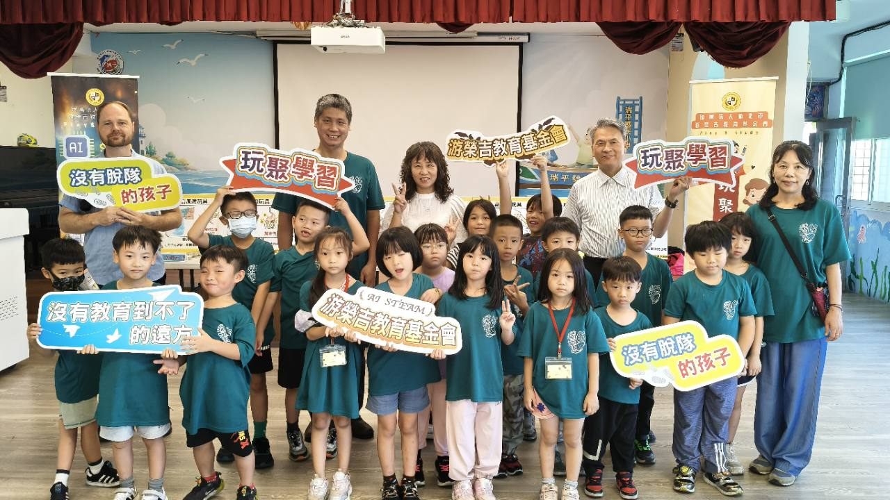 瑞平國小學生與師長在兒童傷害預防課程中合影,手持玩聚學習與教育公益標語