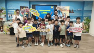 中角國小學生與師長在邏輯程式教育機器人課程始業式合影，手持玩聚學習標語