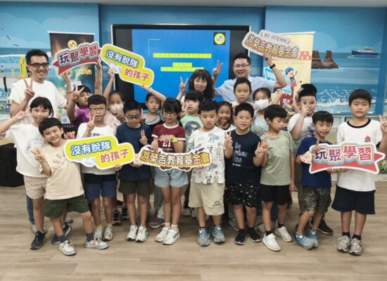 中角國小學生與師長在邏輯程式教育機器人課程始業式合影,手持玩聚學習標語