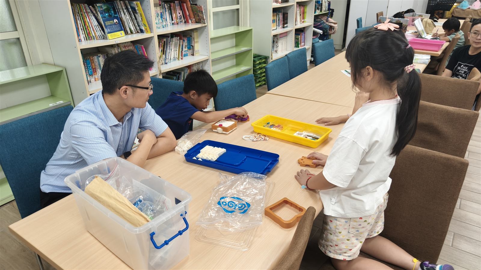 老師在圖書室陪伴中角國小學生操作邏輯程式教育機器人零件與教材