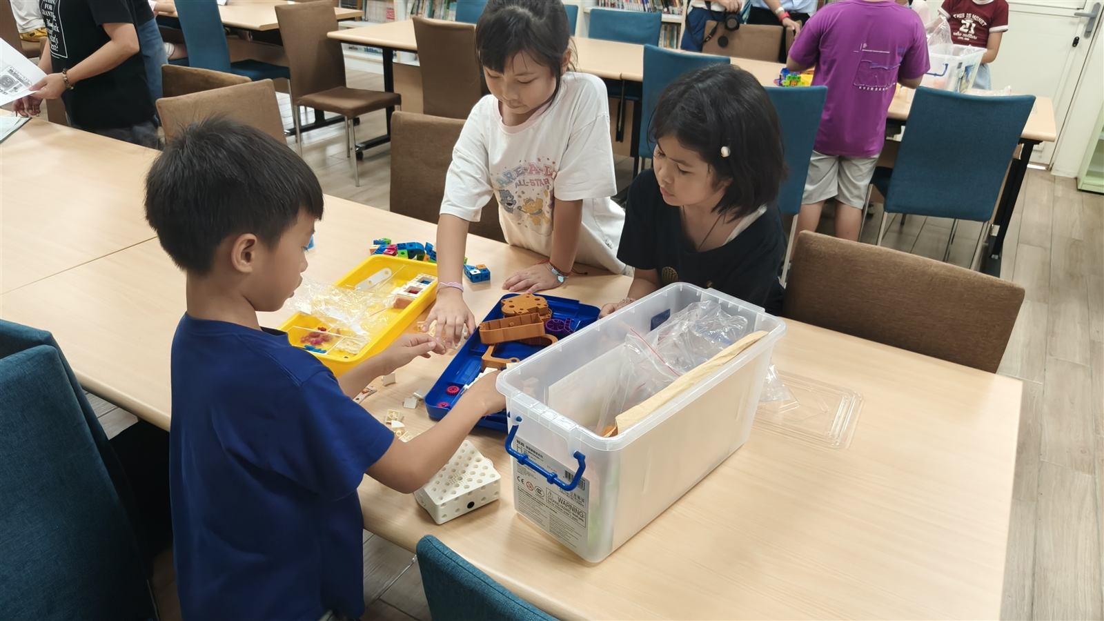 中角國小學生圍在桌邊共同觀察並挑選教育機器人積木零件