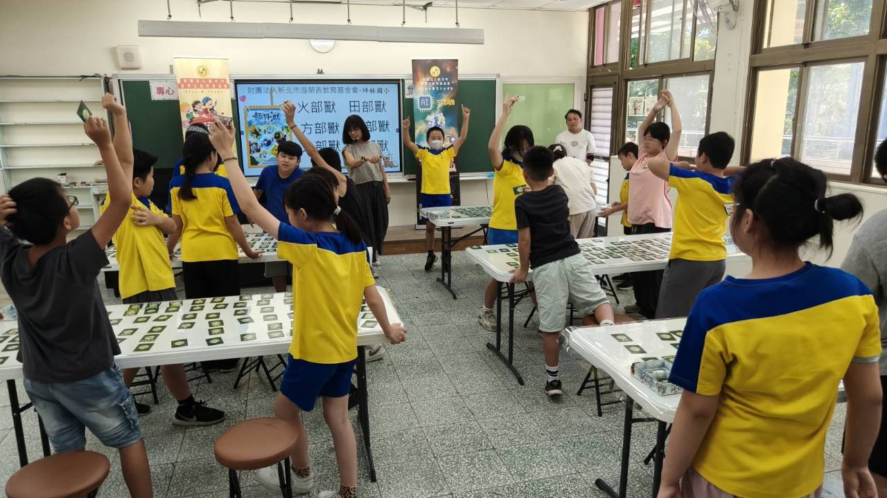 坪林國小學生在部件獸桌遊活動中舉起卡片互動